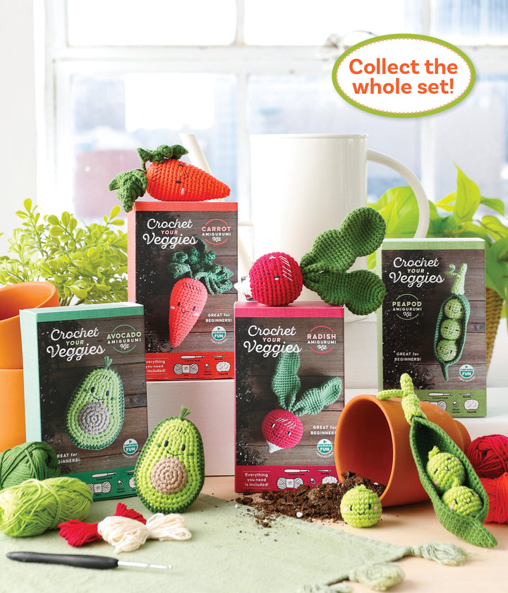 The Schiffer Publishing, Ltd. Crochet Your Veggies Amigurumi Kit Peapod is shown with yarn, beginner crochet tools, and houseplants, while completed crochet veggies sit nearby among spilled soil and a tipped plant pot.